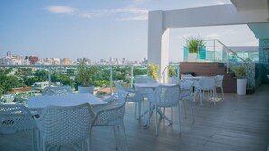 A rooftop terrace with outdoor seating, a staircase, and a city view.