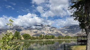 A tranquil lake with mountains in the background, a tree in the foreground, and a wooden structure near the water's edge. - Death Valley Passageway Lake Olancha RV Campsite#4 (Olancha)