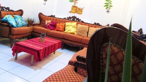 A living room with a sofa, a coffee table, and a chair. There are wall decorations including a bird, a plant, and a fruit basket. - COMFORTABLE & COZY HOUSE IN SAN BLAS (Cusco)