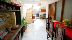 A spacious hallway with a staircase leading to a kitchen area. There are potted plants and a dining area with chairs and a table. - COMFORTABLE & COZY HOUSE IN SAN BLAS (Cusco)