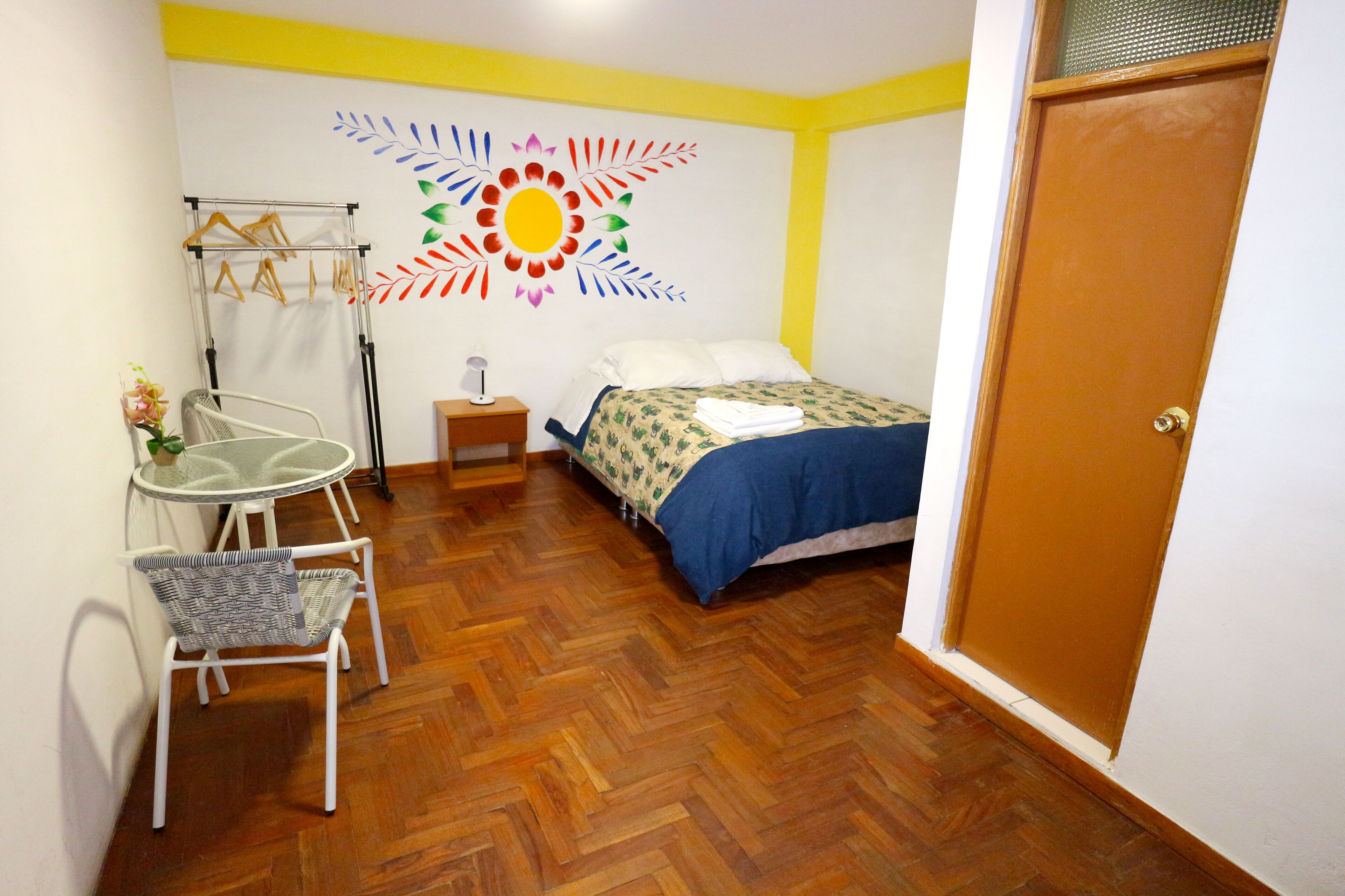 A bedroom with a bed, a chair, a table, and a wall decoration.