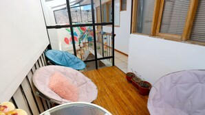 A balcony with a wooden floor, two bean bags, a round table, and potted plants. - COMFORTABLE & COZY HOUSE IN SAN BLAS (Cusco)