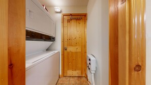 A narrow hallway with a wooden door, a white appliance, and a white device on the wall. - Crystal Forest #31 | 3 Peaks Rentals (Sun Peaks)