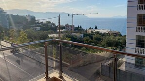 Un balcón con vista a la costa, que incluye edificios y una grúa.