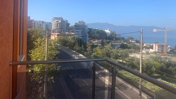 Un balcón con vistas a un paisaje urbano, que incluye edificios y una cadena montañosa distante.