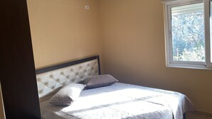 Un dormitorio con una cama, una ventana y una lámpara en el techo.