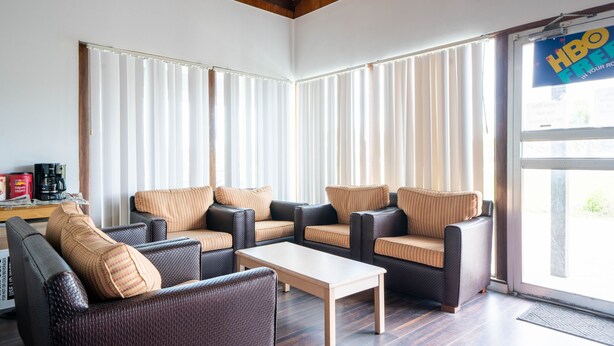 A modern living room with a sofa set, a coffee table, and a large window with blinds. - OYO Hotel Ocala, Fl I-75 (Ocala)