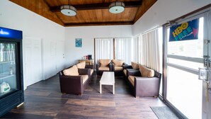 A lobby with a wooden ceiling, a seating area with sofas and chairs, a coffee table, and a glass door with a sign reading "HBO FREE IN YOUR ROOM". - OYO Hotel Ocala, Fl I-75 (Ocala)