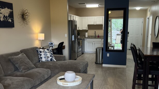 A modern living room with a grey sofa, a coffee table, and a ceiling fan. - Peace and Quiet near Daytona (Holly Hill)