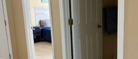 Un corridoio con una porta bianca, pareti beige e pavimento piastrellato.