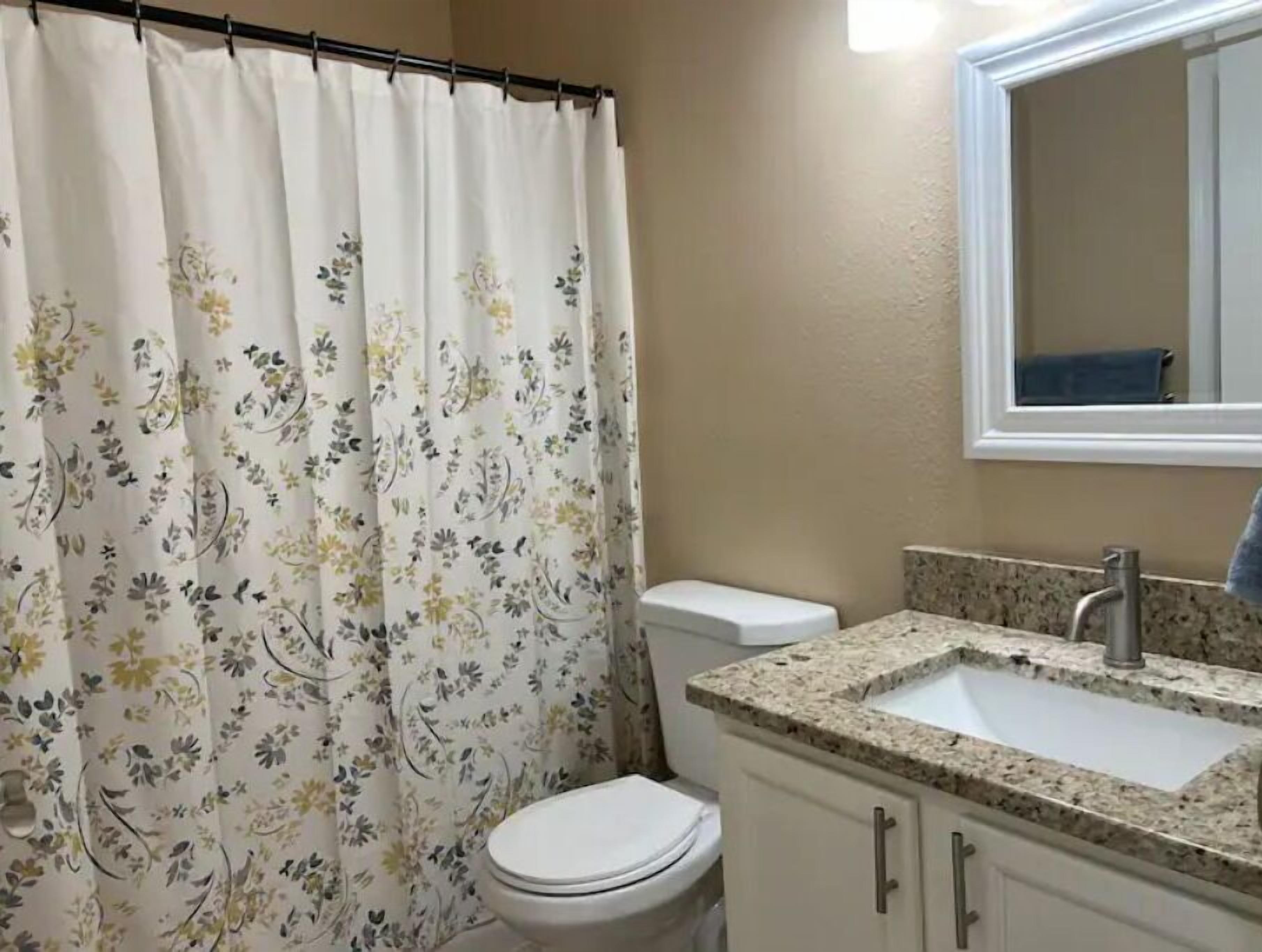 Een badkamer met toilet, wastafel en douchegordijn.