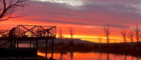 A dock extending into a calm body of water with a sunset in the background.