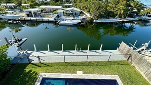 Ein Yachthafen mit vertäuten Booten, einem Schwimmbad und Häusern im Hintergrund.