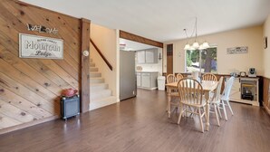 A wooden interior with a dining area, kitchen, and a staircase.