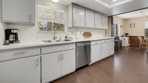 A modern kitchen with white cabinets, a dishwasher, and a coffee maker.