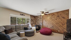 A cozy living room with a sectional sofa, a red bean bag, a fireplace, and a television.