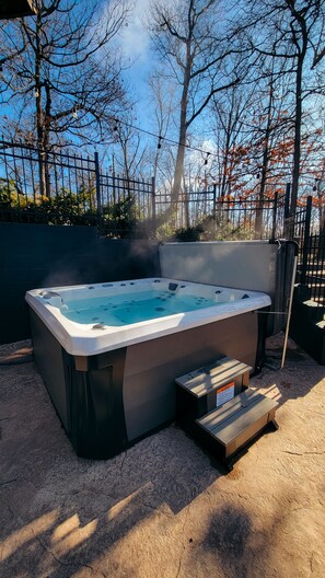 Ein Whirlpool mit einer Holzbank in einer Gartenanlage.