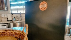 Eine Küche mit einem schwarzen Kühlschrank, einem gewebten Korb und mehreren runden Untersetzern auf der Arbeitsplatte.