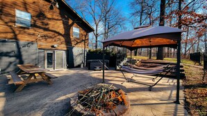Ein Holzhaus mit Terrasse, einer Hängematte und einem Grillplatz.