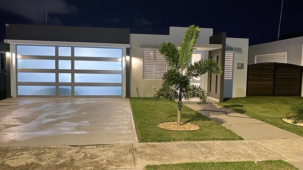 A modern house with a large garage, a small tree, and a well-maintained lawn. - Casa Orillia's Del Mar / 7 minutes from Jobo's Beach  (Isabela)