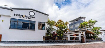 A modern hotel with a spa, featuring a white facade, large windows, and a well-maintained garden with palm trees.