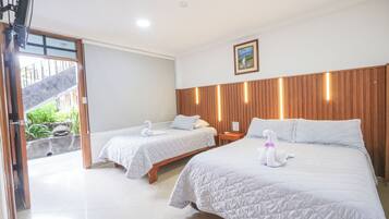 A hotel room with two beds, each with a swan-shaped pillow, a wooden headboard, and a small bedside table.