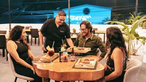 A group of people dining at an outdoor restaurant with a view of a building in the background. - Fernandina Hotel & Spa Galápagos (Puerto Ayora)