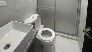 Een kleine, moderne badkamer met toilet, wastafel en douche.