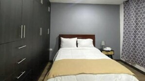 Een slaapkamer met een bed, een kledingkast, een nachtkastje en een behang met patroon.