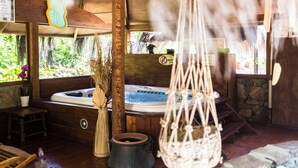 A wooden cabin with a hot tub, a stone fireplace, and a hanging macrame chair. - Villa la Sugherella Tuscany sea, swimming pools spa family golf horse gym kneipp (Gavorrano Toscana)