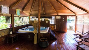 A wooden-roofed hot tub area with a bench and a small table. - Villa la Sugherella Tuscany sea, swimming pools spa family golf horse gym kneipp (Gavorrano Toscana)