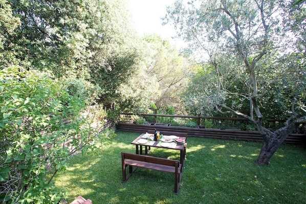 A wooden table with a bench in a lush garden setting.