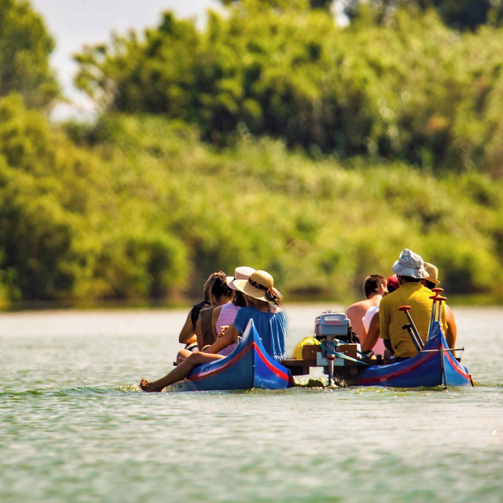 Un groupe de personnes se trouve dans un bateau sur une étendue d’eau, entouré de verdure.