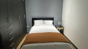 A bedroom with a bed, a wardrobe, and a nightstand.