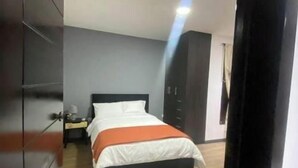 A modern bedroom with a bed, nightstand, and wardrobe.