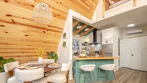 A modern kitchen with white cabinets, a wooden ceiling, and a bar area with stools.