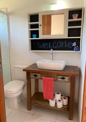 A compact bathroom with a white toilet, sink, and blackboard above the sink.