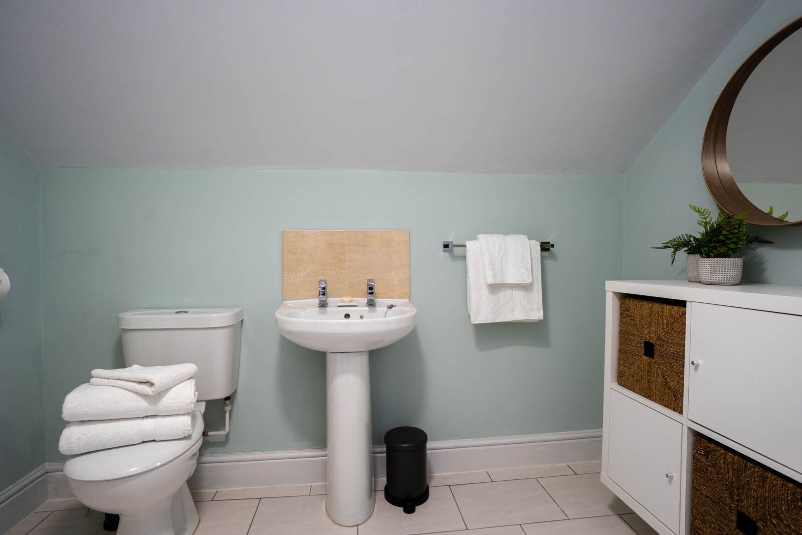 A bathroom with a toilet, sink, and a cabinet with a mirror.