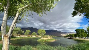 Un río con árboles y montañas al fondo.