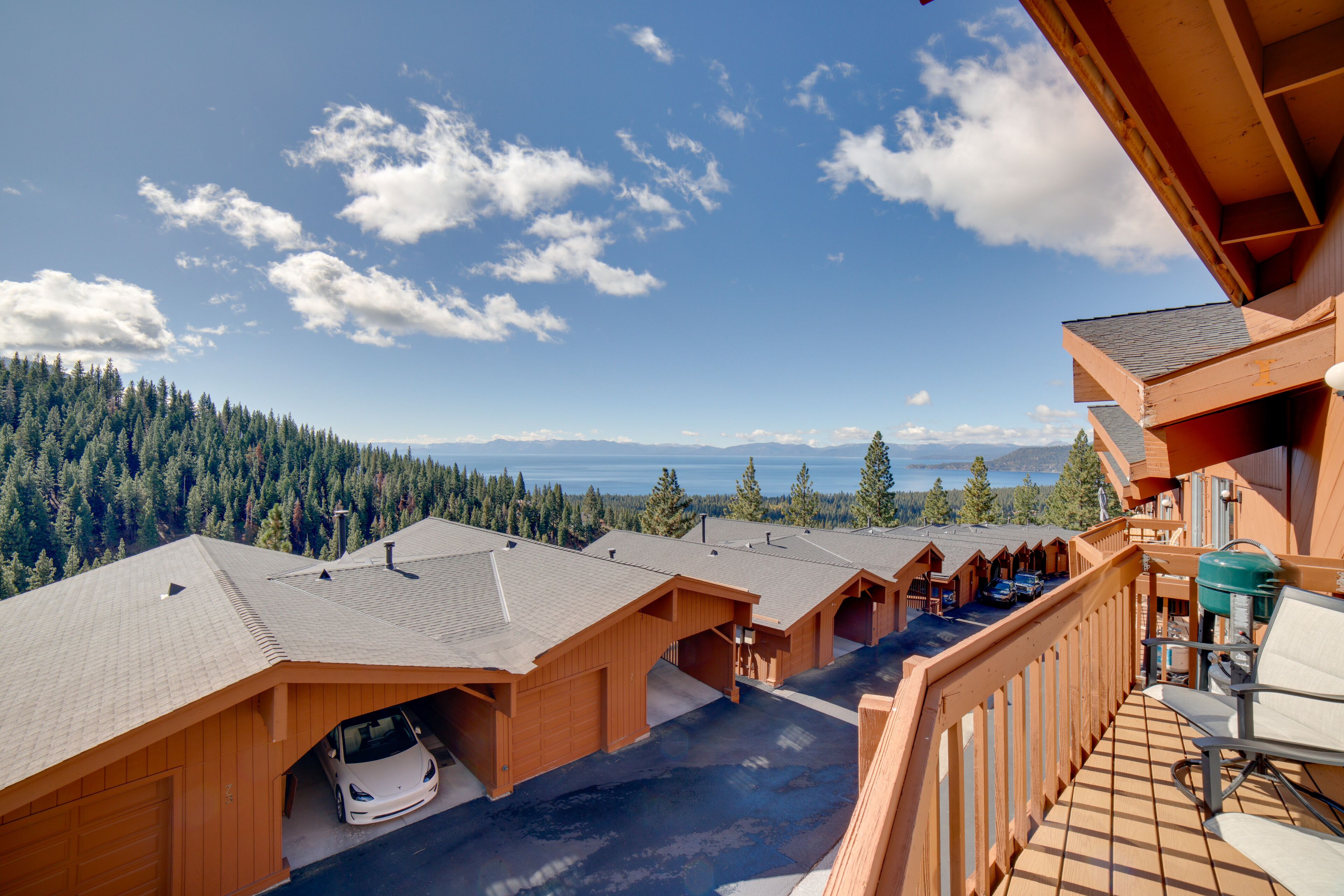 Eine Holzhütte mit Garage, einem Balkon mit Stuhl und Blick auf einen Wald und Berge.