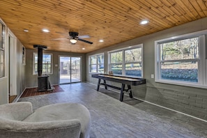 A spacious room with a pool table, large windows, and a ceiling fan.