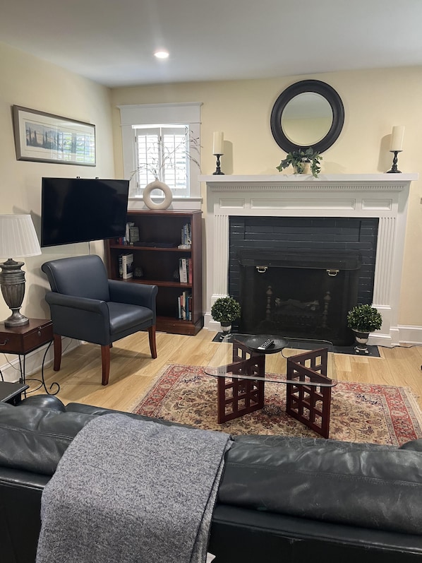 Una sala de estar con chimenea, televisor, estantería y sofá.