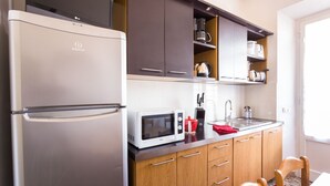 A compact kitchen with a stainless steel refrigerator, a microwave, wooden cabinets, and a sink. - Casa Laura Follonica  200 metres from the sea/beach Wifi air/condition tv/sat (Follonica)