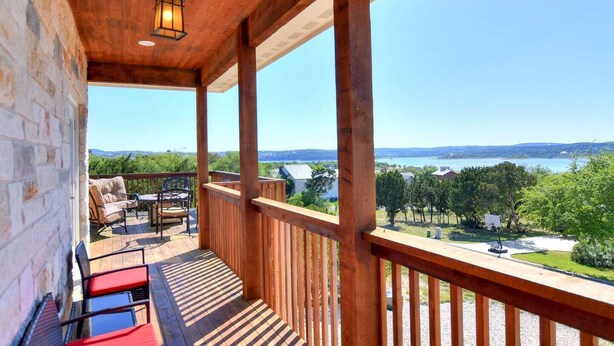A wooden balcony with a view of a lake and distant hills.