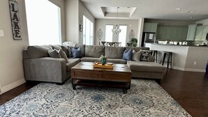 A spacious living room with a large sectional sofa, a coffee table, and a patterned rug.