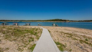 Een strand met een betonnen pad dat leidt naar verschillende kleine steigers boven het water.