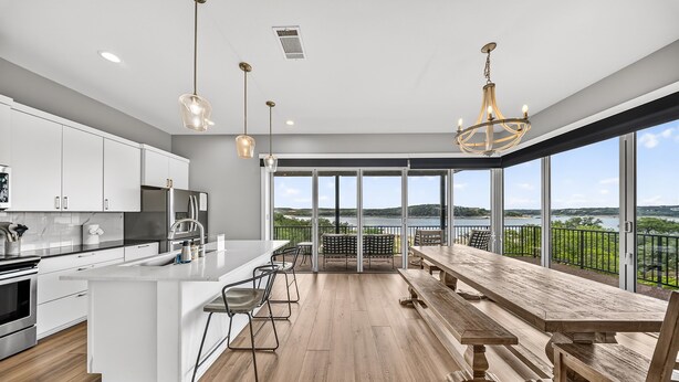 Een moderne keuken met een groot eiland, barkrukken en een eethoek met uitzicht op het meer.