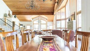 A spacious dining area with a long wooden table, chairs, and a chandelier. - Stunning mountainside home in West Vail (Vail)