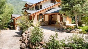 A two-story house with a stone foundation, wooden exterior, and a stone pathway leading to the entrance. - Stunning mountainside home in West Vail (Vail)