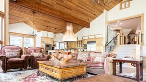 A spacious living room with a high ceiling, wooden beams, and a large rug. - Stunning mountainside home in West Vail (Vail)